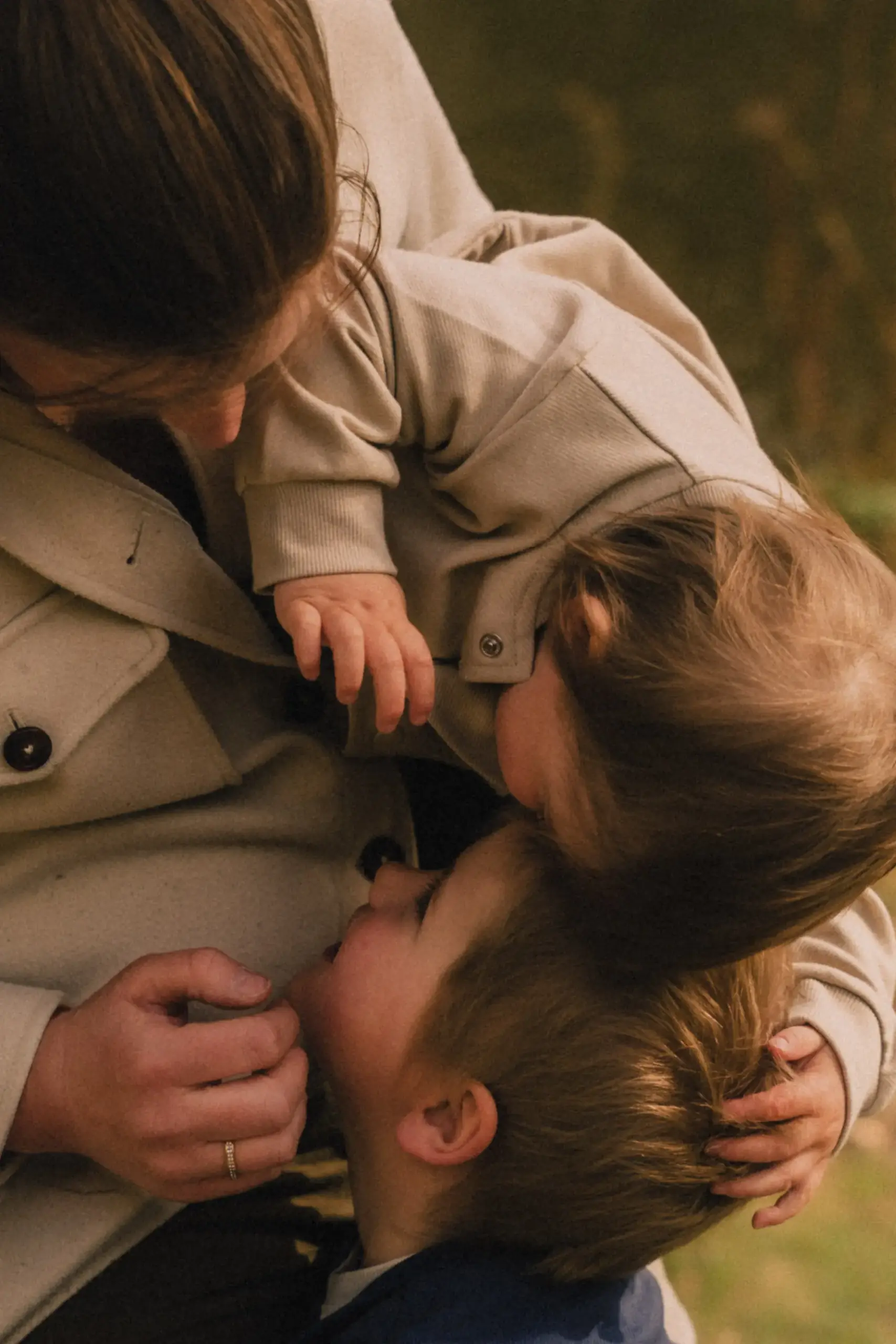 Mutter umarmt zwei kleine Kinder in der Natur