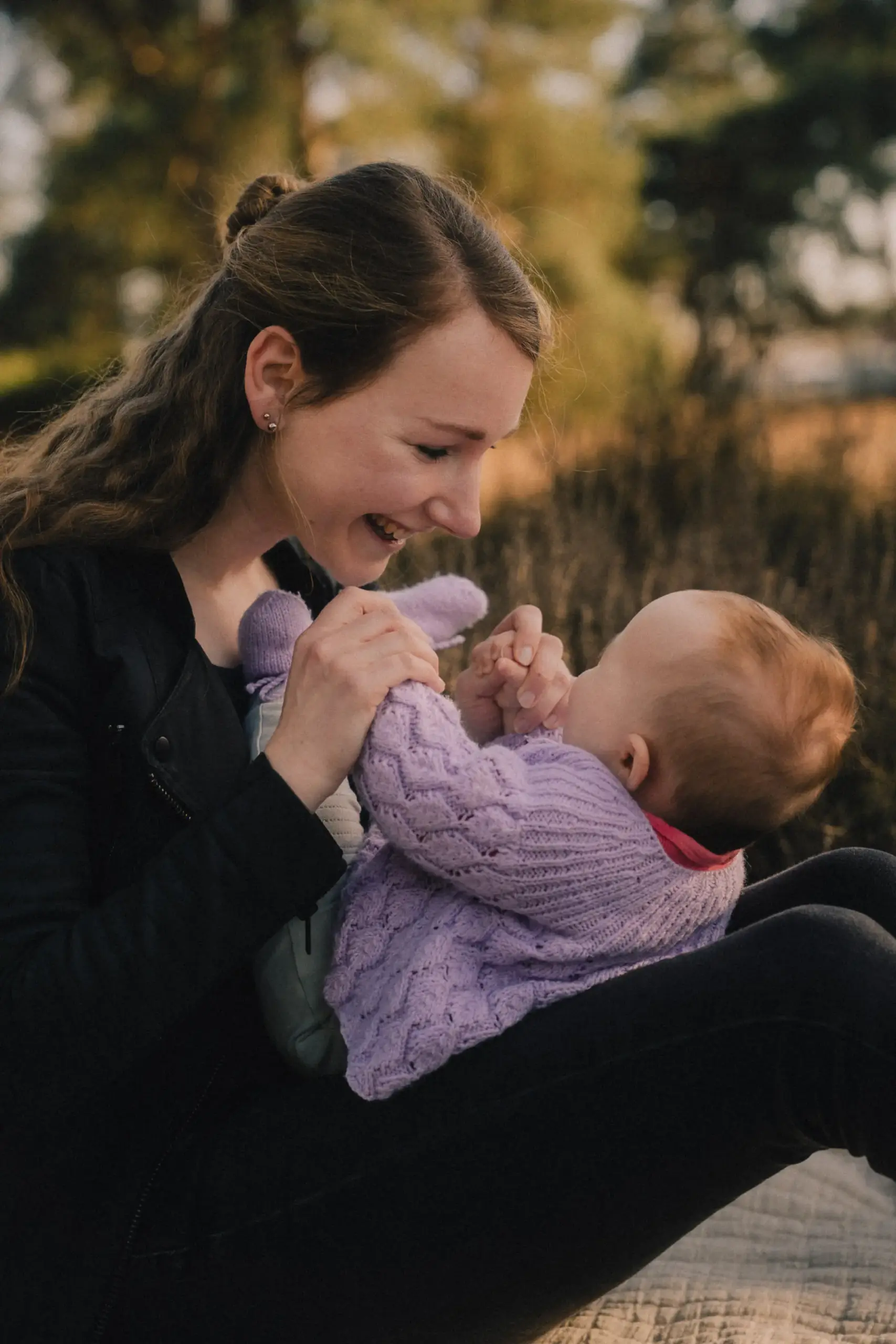 Mutter und Baby spielen lachend in der Natur